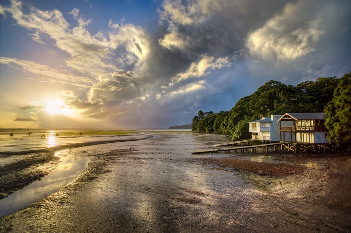 Houses on stilts by the water at sunset
