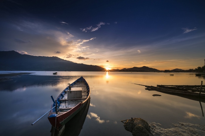 Boat on calm water at sunset with mountains