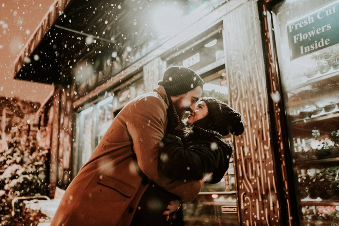 Couple kissing in the snow outside a flower shop
