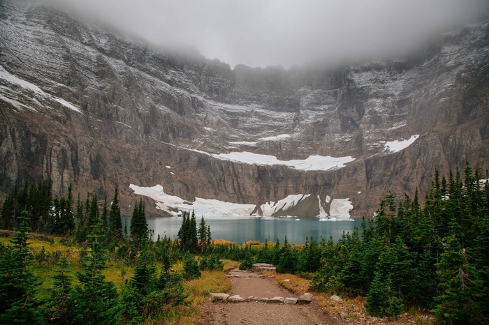 Foggy mountain lake with snow and pine trees
