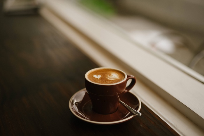 Brown cup of cappuccino with latte art on a saucer