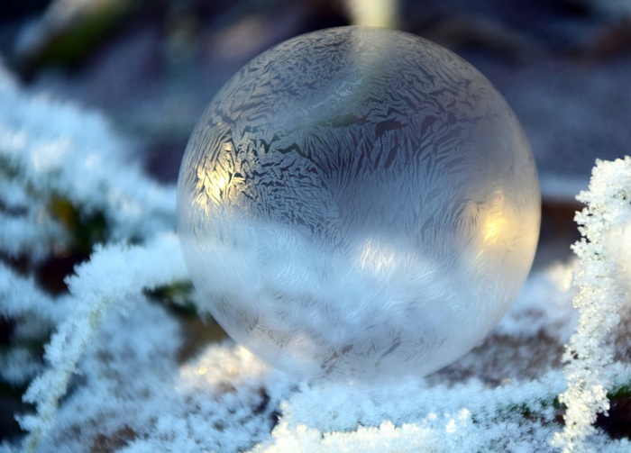 Frozen soap bubble with frost patterns in winter