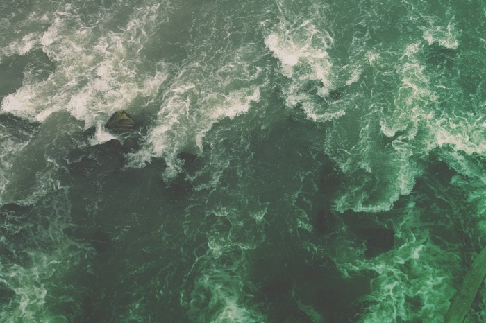 Green ocean waves crashing over rocks