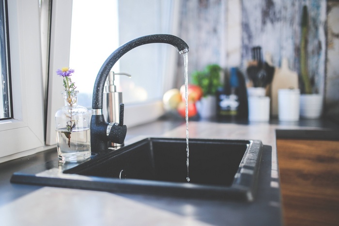 Black kitchen sink with running water from a faucet