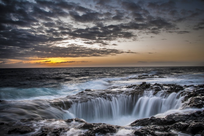 Ocean waves crashing into a rocky shore at sunset