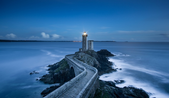 Lighthouse on a rocky island with a stone bridge
