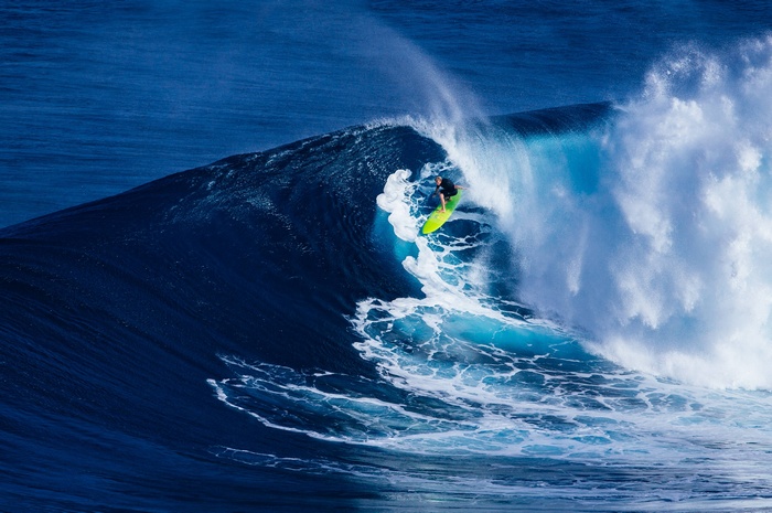 Surfer riding a large blue wave