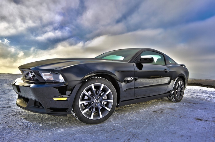 Black Ford Mustang 5.0 parked on a snowy landscape