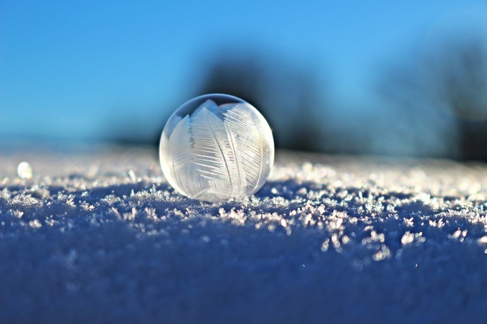 Frozen bubble with ice crystals on snow