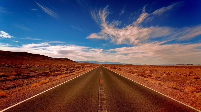 Desert road stretching into the distance under a blue sky