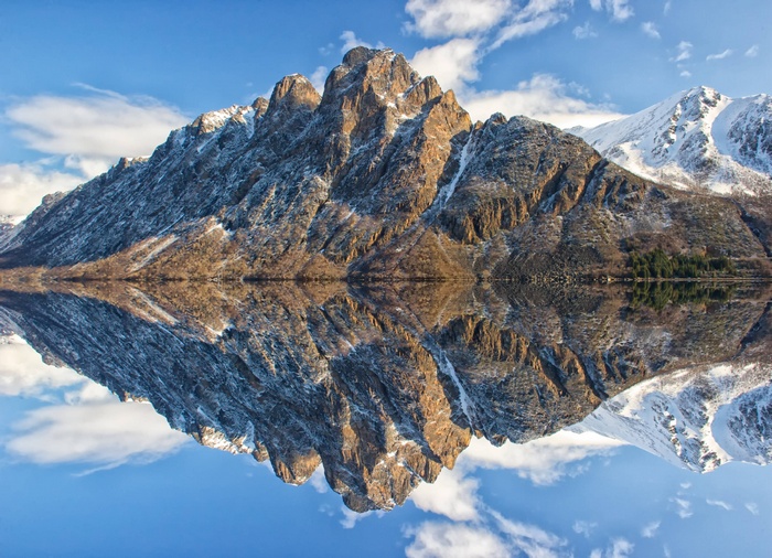 Mountain reflected in still water under a blue sky