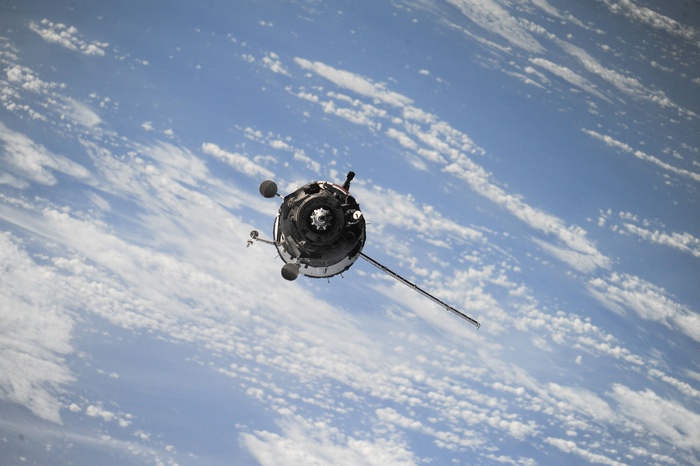 Space satellite orbiting Earth with clouds