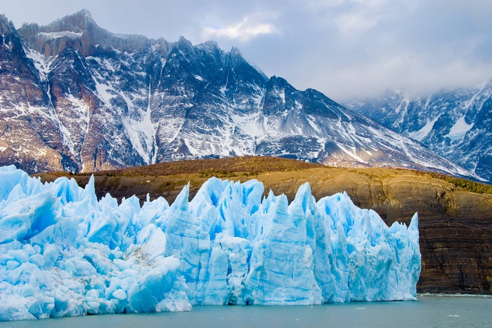 Blue glacier ice in front of snowy mountains in Patagonia