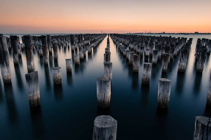 Wooden pillars in the water at sunset