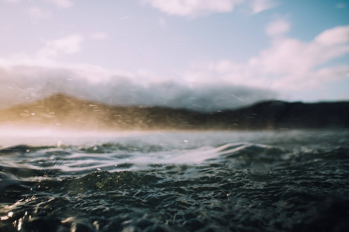 Rain falling on ocean waves with mountains in background
