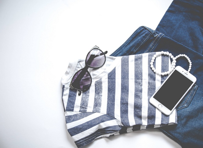 Striped shirt, sunglasses, phone, and denim laid out