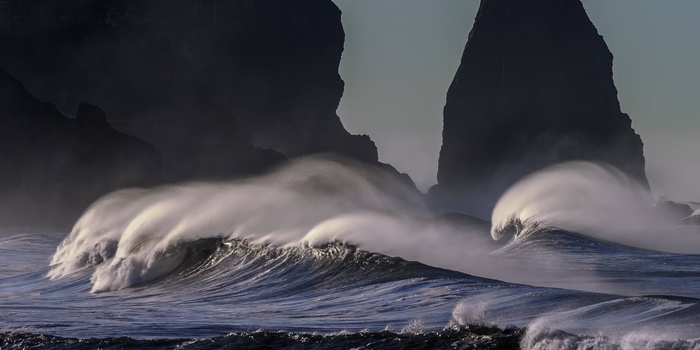 Waves crashing against dark rock formations on the coast