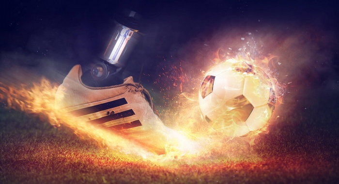 Soccer boot kicking a flaming football