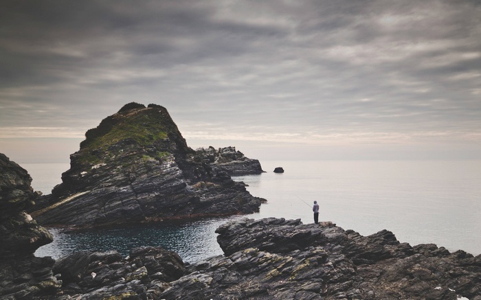 Fisherman on rocky coast with calm sea
