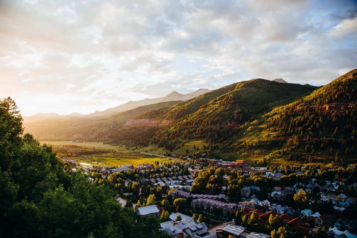 Town nestled in a valley with mountains at sunset