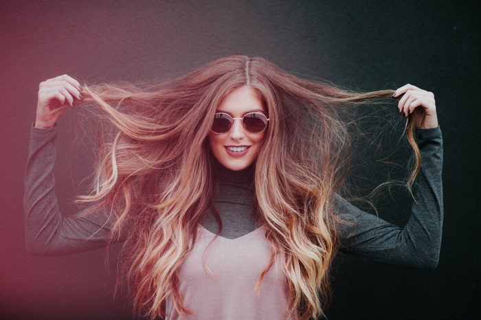 Woman with long, wavy blonde hair wearing sunglasses