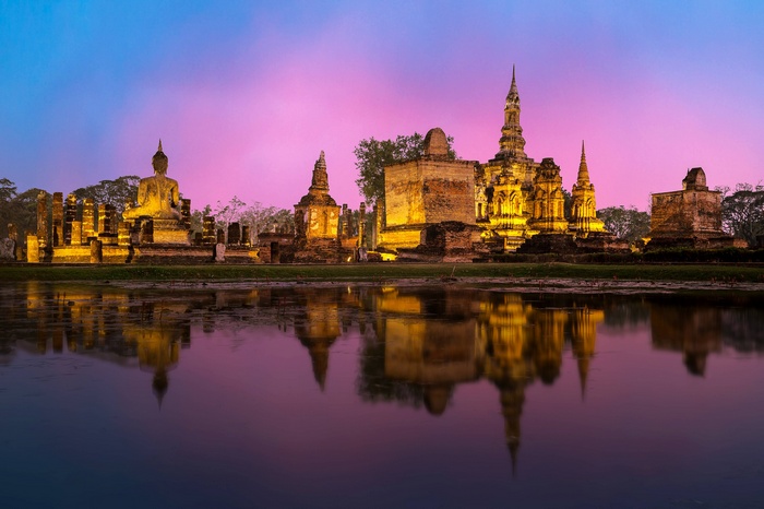 Ancient Buddhist temples and Buddha statue at dusk