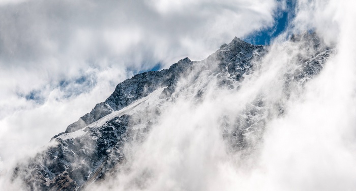 Snowy mountain peak shrouded in clouds