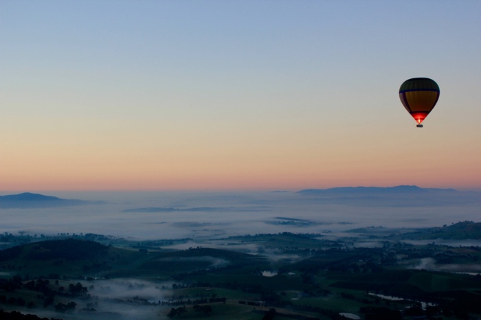 Hot air balloon over misty landscape at sunrise