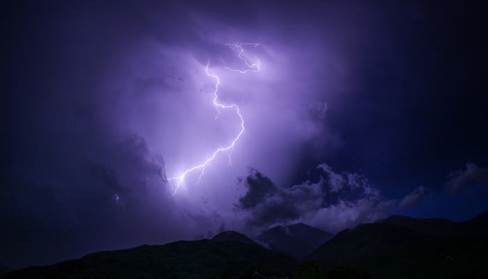 Lightning strikes over dark mountains during a thunderstorm