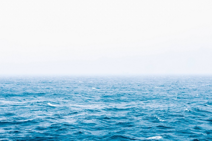 Blue ocean waves under a hazy sky