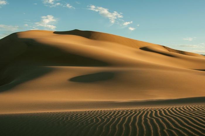 Sand dunes in the desert under a blue sky
