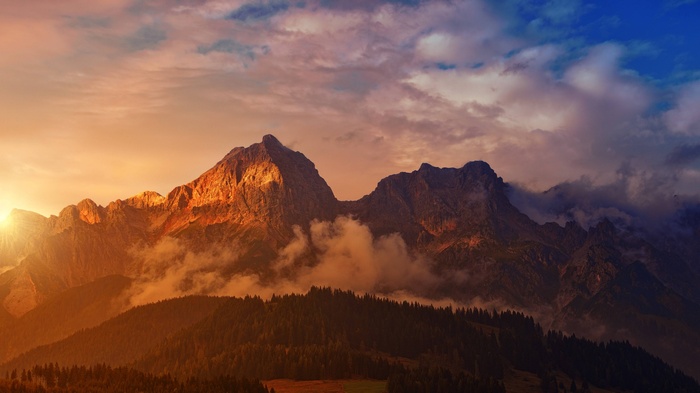 Sunset over majestic alpine mountains with clouds