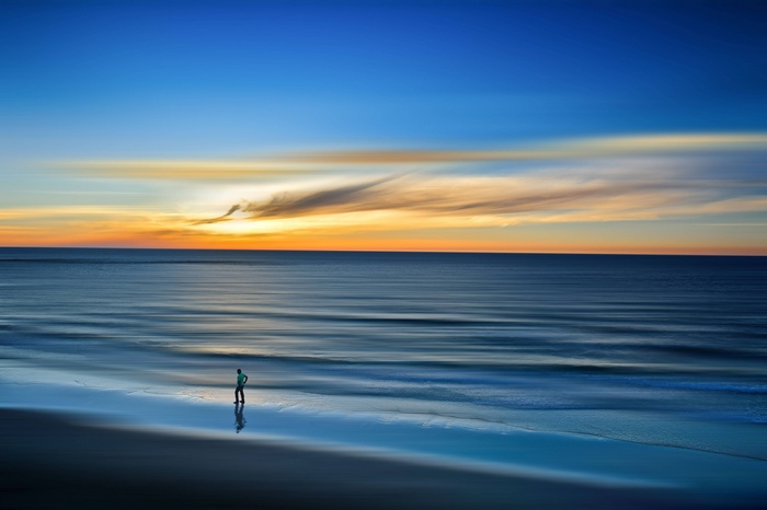 Man walking on a beach at sunset