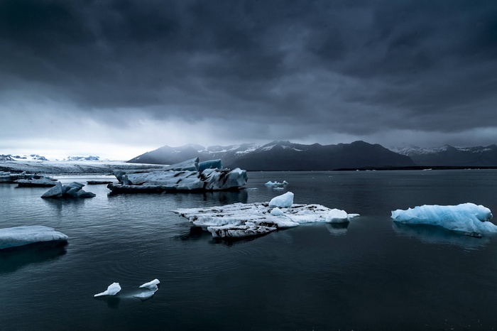 Icebergs floating in a glacial lagoon under a cloudy sky