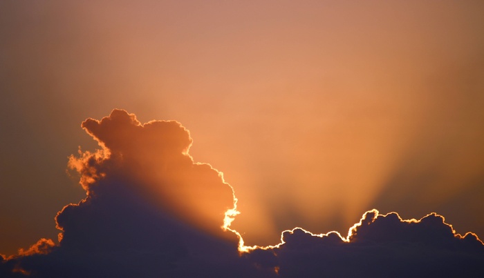 Sunbeams shining through dark clouds at sunset