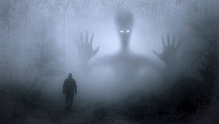 A man walks towards a giant alien in the fog
