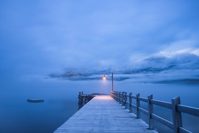 Misty morning pier with a single lamp post