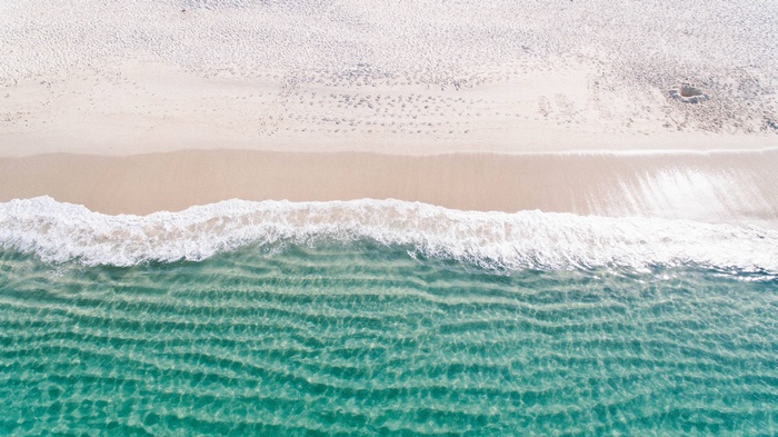 Aerial view of a sandy beach and clear ocean water