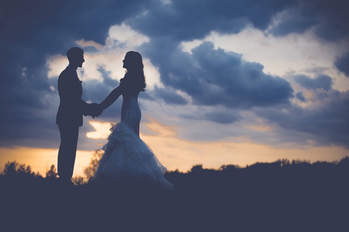 Couple holding hands at sunset during a wedding