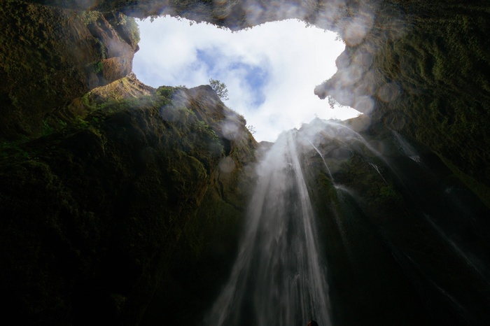 Looking up inside a cave at a waterfall