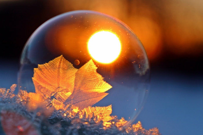 Frozen soap bubble with ice crystals and sunset reflection