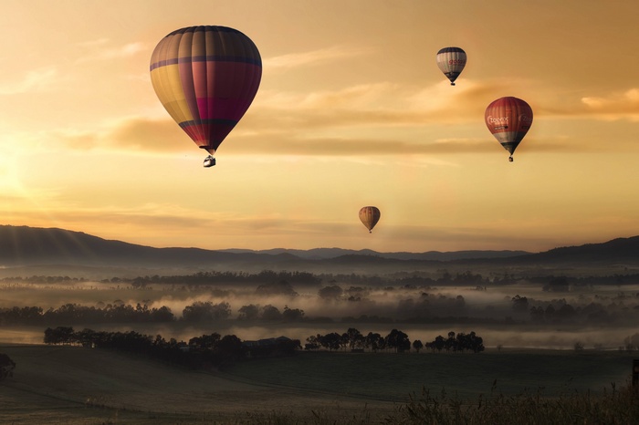Hot air balloons floating over misty landscape at sunrise