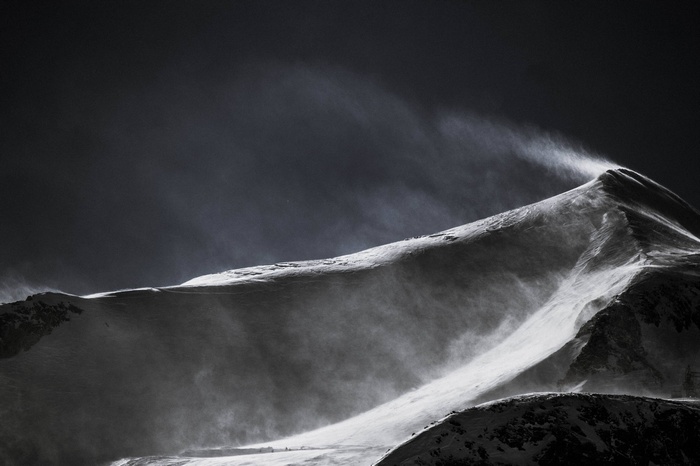 Snowy mountain peak with wind blowing snow