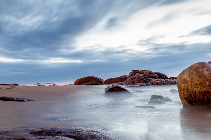 Ocean waves crashing on rocky shore with cloudy sky