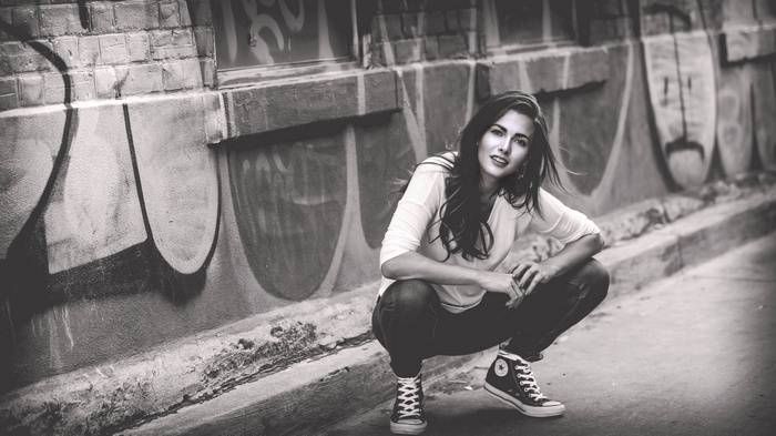 Woman crouching in front of graffiti wall