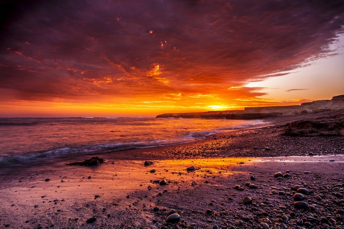 Sunset over a rocky beach with ocean waves