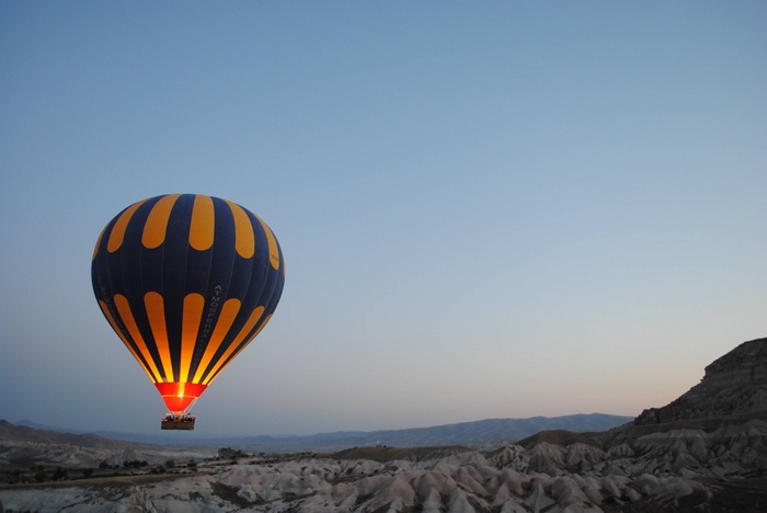 Hot air balloon flying over rocky landscape at dawn