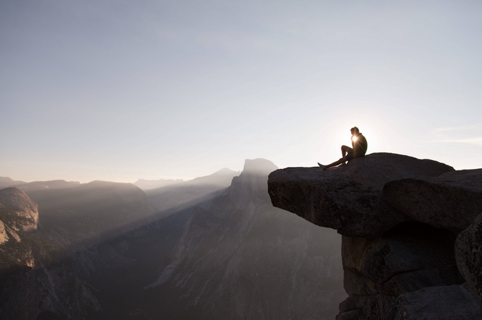 Person sitting on a cliff edge in Yosemite National Park