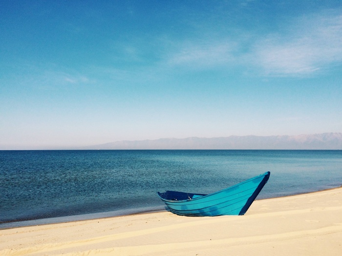 Blue boat on a sandy beach by the ocean