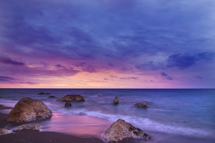 Ocean rocks at dusk with purple and pink clouds